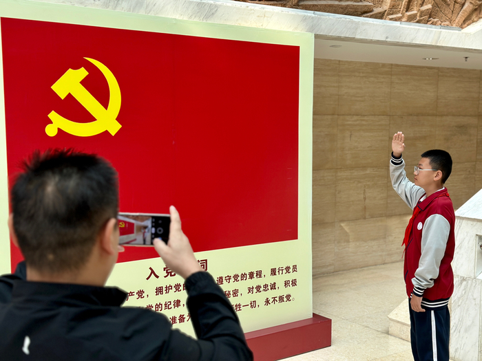 图为游客在党旗前拍照留念。