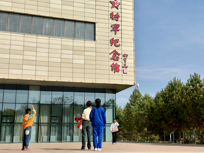 图为游客在纪念馆前打卡拍照。