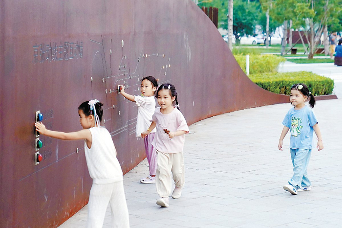 小朋友们在京张铁路遗址公园内的京张动线主题互动墙体验火车信号灯。