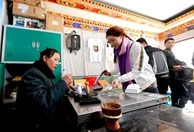 △“天上西藏”邮局珠峰店工作人员措姆正在给游客准备邮寄的明信片盖戳。人民政协报记者 田福良 摄