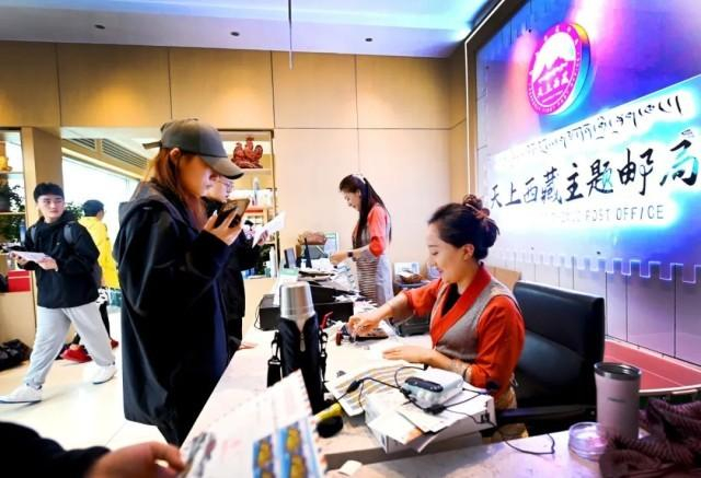 △“天上西藏”主题邮局工作人员正在给游客即将寄出的明信片加盖邮戳。 人民政协报记者 田福良 摄