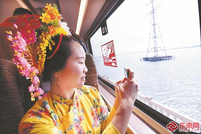 来自泉州的蟳埔女用手机拍摄车窗外的风景。 本报记者 林辉 摄