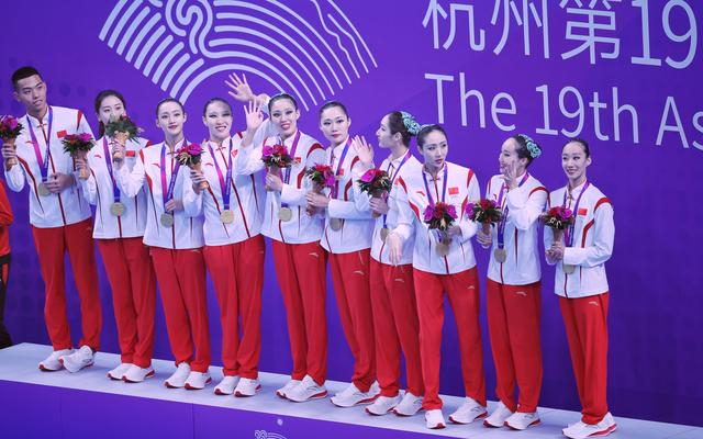 中国花游队登上最高领奖台，石浩玙（左）成为历史首位男子花游亚运冠军。  新京报记者 薛珺 摄