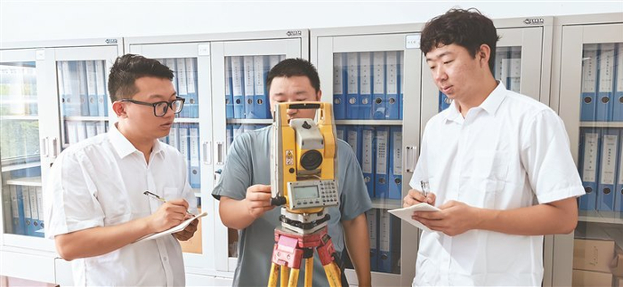     新入职大学生正在向老职工学习矿山测量技术。