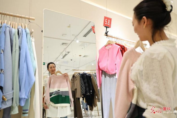 2023年10月1日，在位于重庆市沙坪坝区土主街道的一家综合商超，前来购物的旅客正在挑选服饰。（孙凯芳摄/光明图片）