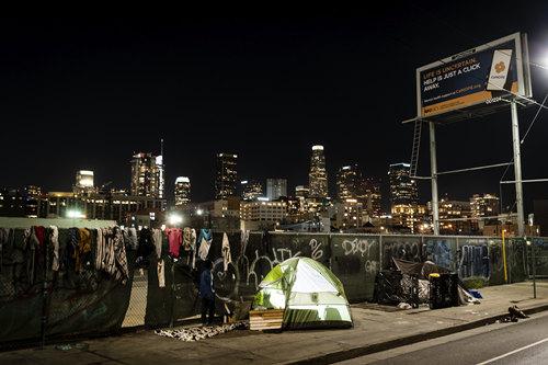 2月8日，美国加州洛杉矶，城市天际线映衬着一个无家可归者的帐篷。（图片来源：视觉中国）