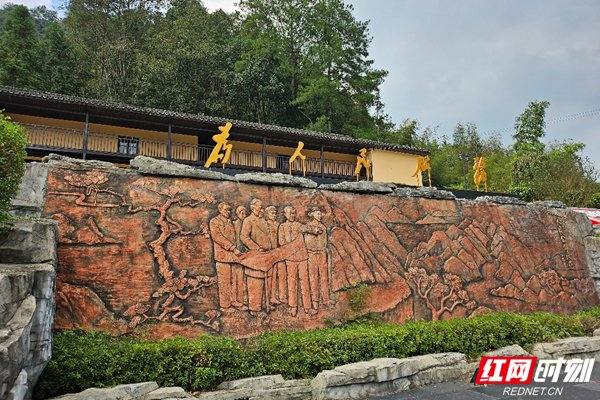 喻杰故居前，喻杰当年带领家乡人民绿荒山，兴水利场景的石壁画。