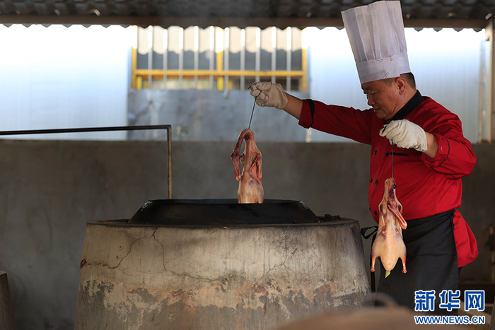 赵学舟从焖炉里取出烤鸭（摄于5月17日）。新华网 赵普凡 摄