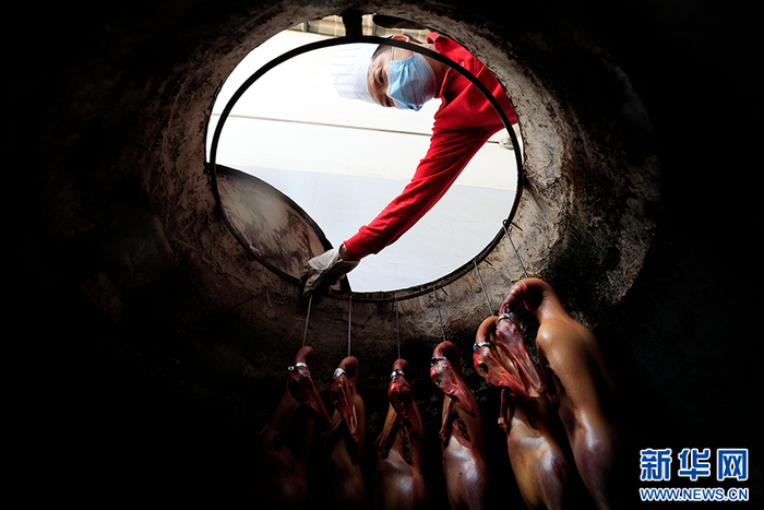 兰红江把鸭子放入烤炉（摄于5月17日）。新华网 赵普凡 摄