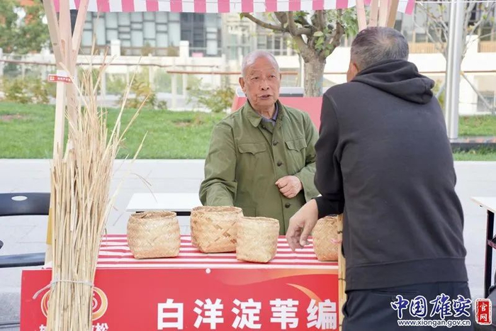 白洋淀苇编艺人与群众交流苇编技艺。中国雄安官网赵伟彤摄
