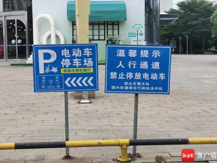 　　10月18日上午10点，日月广场外侧人行道上有禁止停放电动车告示牌和停车场引导牌。记者 李文韬 摄