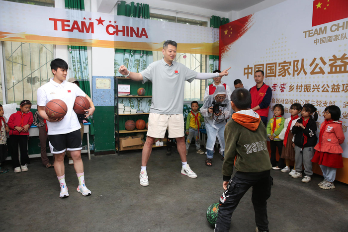 莫科（灰衣白裤）给孩子们传授篮球技能 图据IC photo