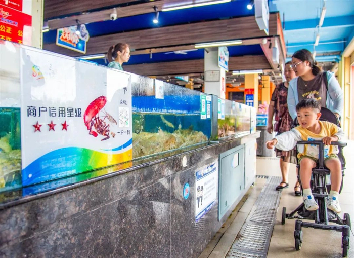 在位于三亚湾的龙兴海鲜广场海鲜销售及加工摊位前，均张贴“商户信用星级”信息及“一户一码”。刘琪成 摄