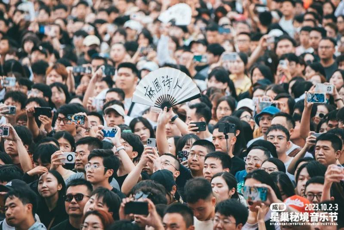 音乐节现场，一名观众举起了写着“麻园诗人”的扇子