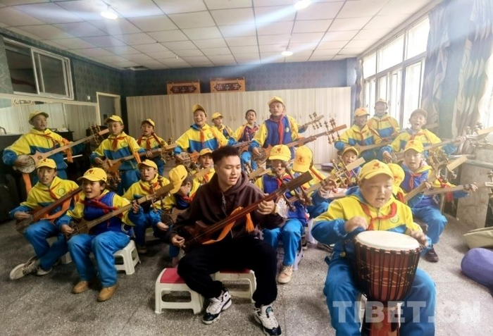 图为在学校文化宫,音乐老师旦增桑布带孩子们上扎木念弹唱课,童声和