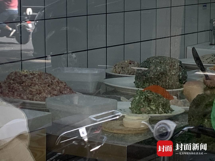 某饺子连锁店，透明橱窗内的工作人员正在包饺子。封面新闻见习记者 何金蓝摄影