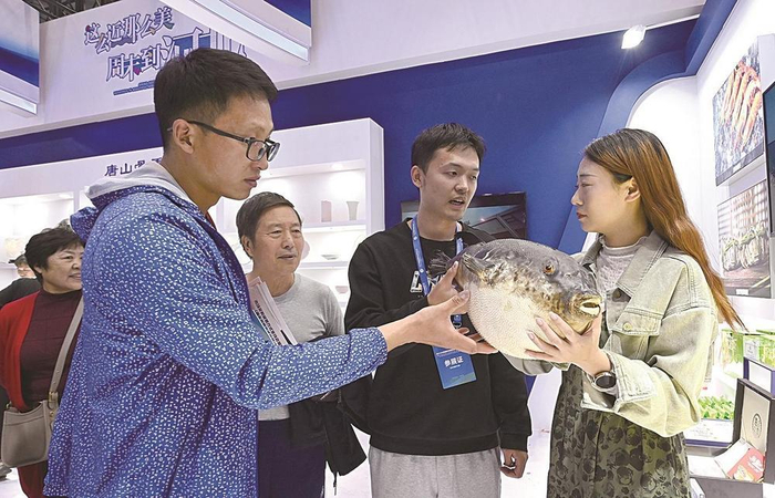     工作人员向来宾介绍河豚鱼养殖、食用知识。                                            本报记者 杜雯拓 张北男 刘洪超 摄