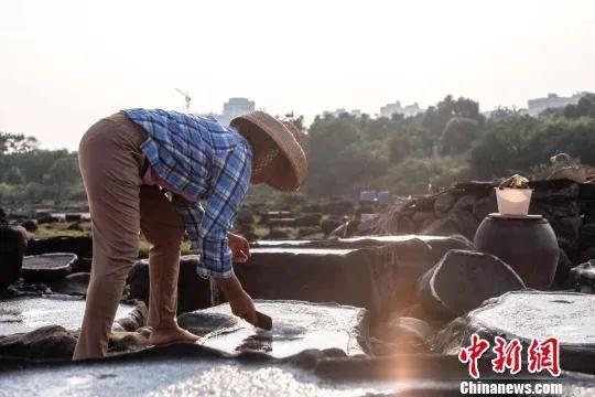 图为盐田村村民在千年古盐田内晒盐。洪坚鹏 摄(资料图)