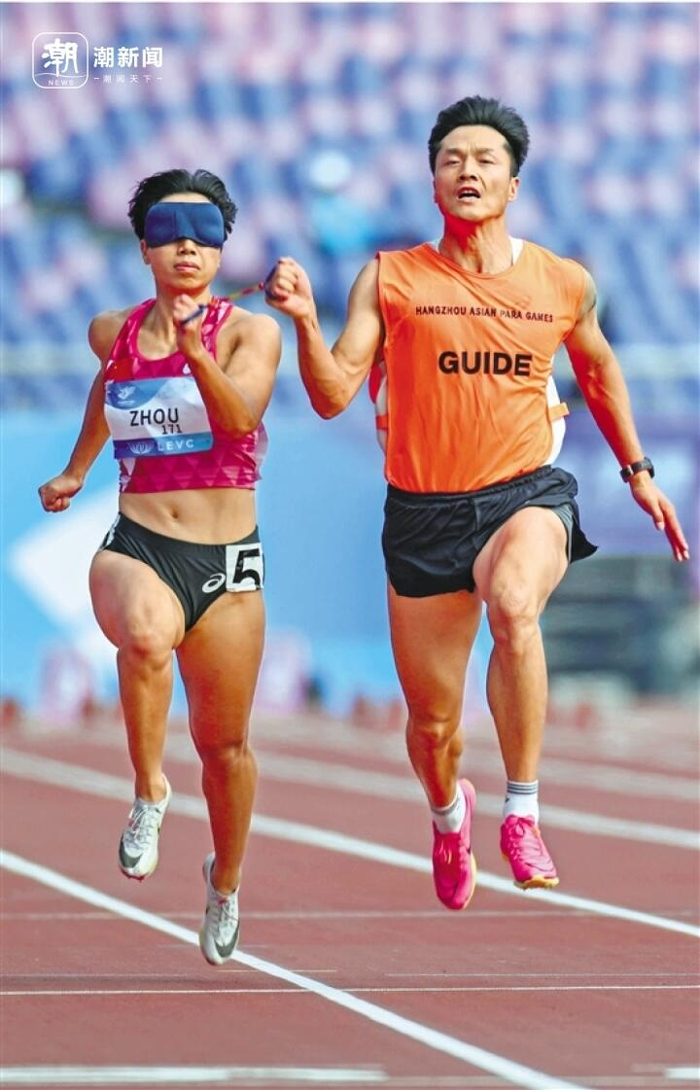 在女子100米t11比赛中,周国华(左)在领跑员贾登璞的协助下完成比赛.