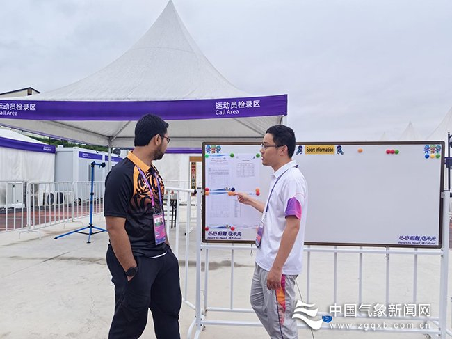 10月4日5时，在淳安赛区公路自行车项目比赛现场，气象派驻人员正在为运动员领队说明天气情况。图/文 叶蕾