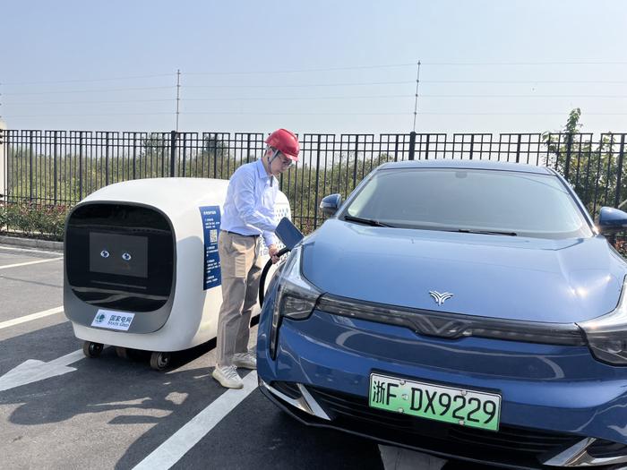 2023年10月17日，国网浙江电力工作人员在乌镇使用首台智能移动充电机器人为新能源汽车充电。新华网发 沈佳炜 摄