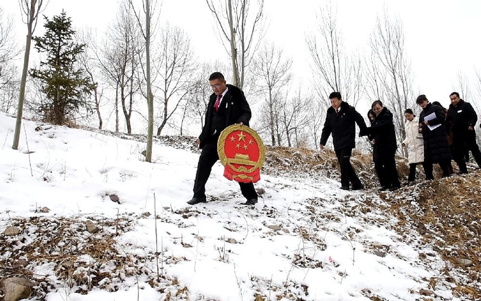 互助土族自治县人民法院家事审判团队法官迎着漫天的飞雪，手捧国徽，入村开展巡回审判。省高级人民法院供图