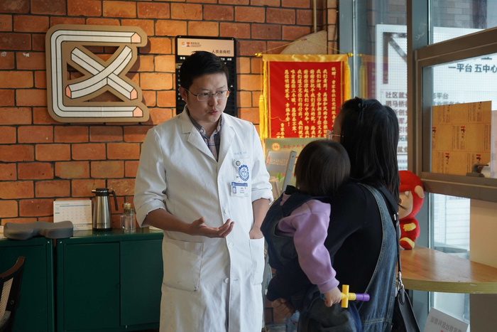 四川大学华西医院小儿骨科杨晓东医生与前来义诊的家长交流