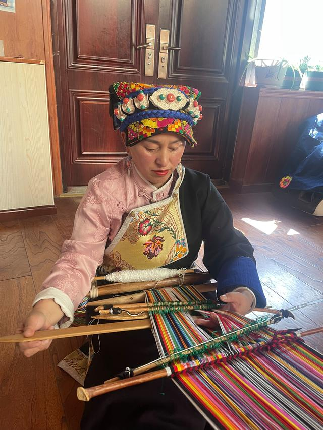 仁珍初正在编织服饰。新京报记者 熊丽欣 摄