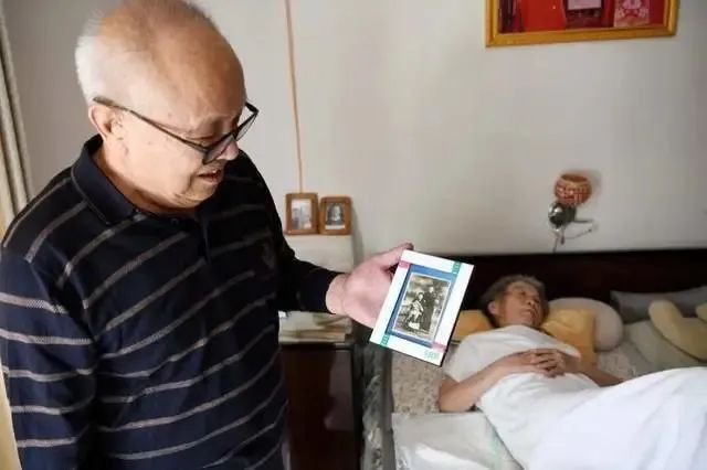 10月26日，王怀民老人在卧室手拿着老伴儿小时候的照片。健康时报记者牛宏超摄