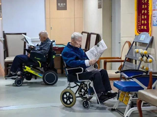 10月26日下午，在养老机构走廊里看报纸的老人。赵苑旨摄