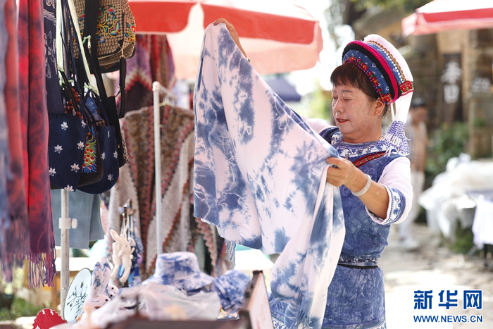 龙素云正在整理摊位上的扎染（摄于9月19日）。新华网 赵普凡 摄