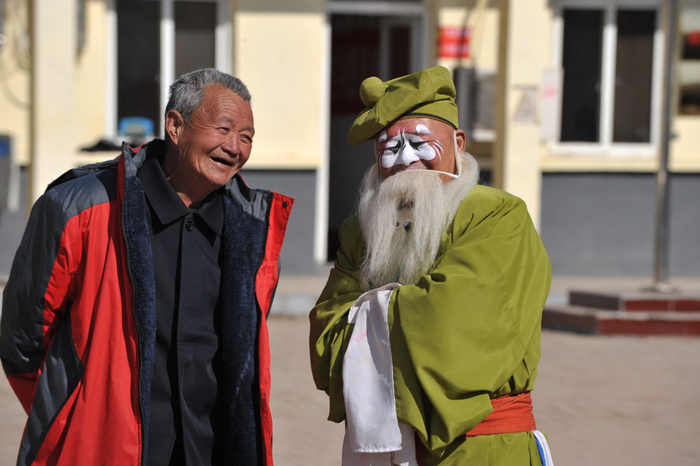 2022年2月22日，在石家庄市深泽县故城村，一名村民与深泽县坠子剧团演员交流。新华社发（资料片）