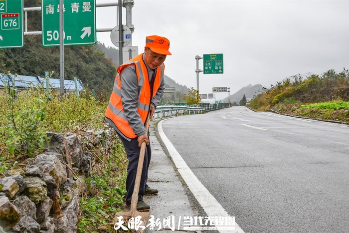 龙俊吉在清理路边杂草。（戴正国 摄）