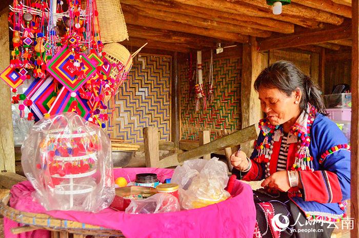 传统木楼中,一位德昂族妇女制作着极具特色的德昂织锦