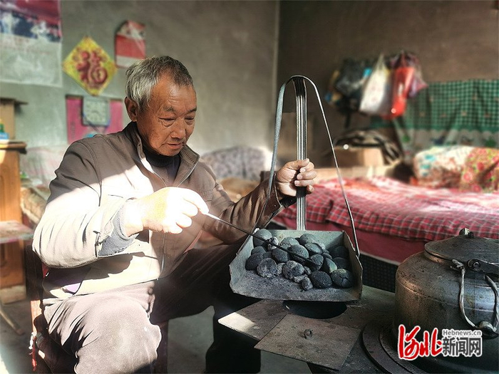 11月14日,武安市管陶乡坟峧村68岁村民杨保生给取暖用的煤炉添加洁净