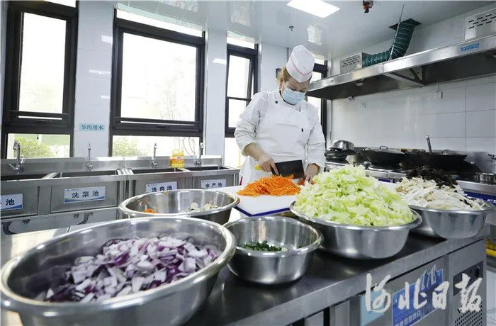 图为11月22日，在固安县第三幼儿园的厨房，工作人员正在切菜。通讯员孙瑞琳摄