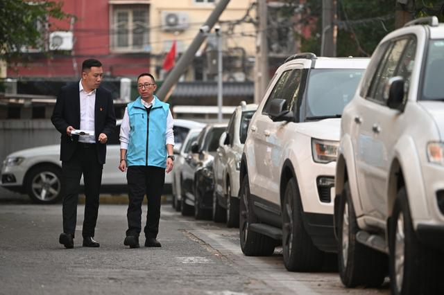 10月24日，胡浩正在小区内与同事检查车辆停放。确保停车有序进行。新京报记者 陶冉 摄