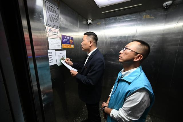 10月24日，胡浩正在小区内与同事检查电梯维护情况，确保电梯正常运行。新京报记者 陶冉 摄