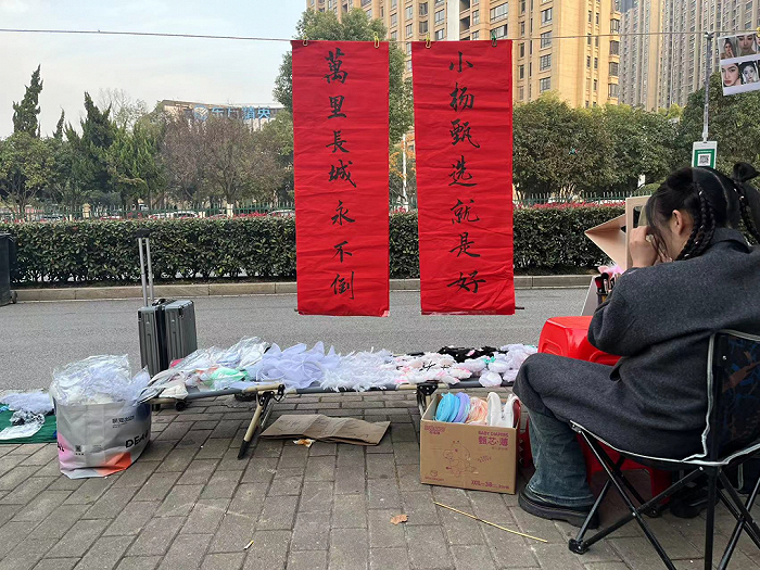 ▲ 演唱会开始前，场馆附近有人打出支持小杨臻选的旗号，摆摊化妆编发。图/常芳菲