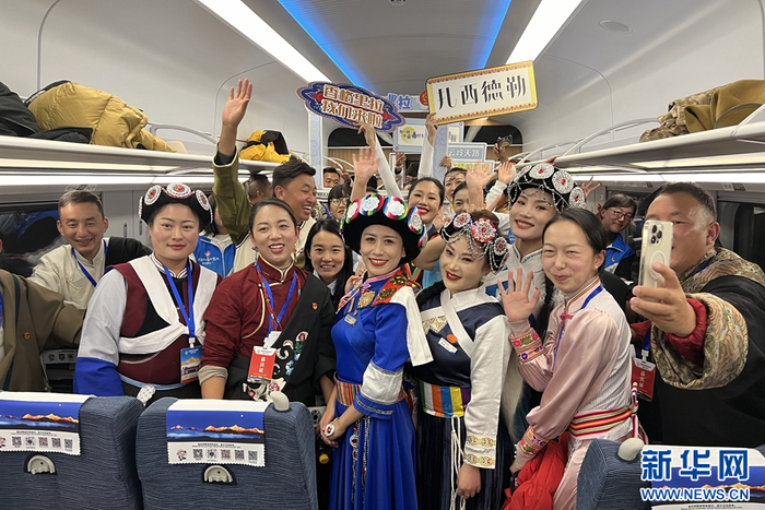 从香格里拉站发出的首趟复兴号动车上，各族群众、列车工作人员合影留念（摄于11月26日）。新华网发（王一翔 摄）