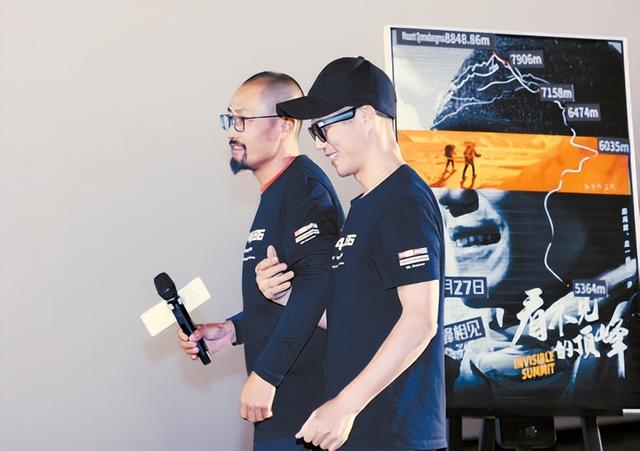 《看不见的顶峰》全国首映礼上，张洪与向导强子走过海报。 IC photo供图