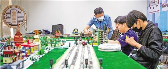 3月14日，在泰国大城府大城技术学院鲁班工坊铁院中心，教师（左一）在高铁运营沙盘教学区指导学生。 新华社记者 王腾 摄