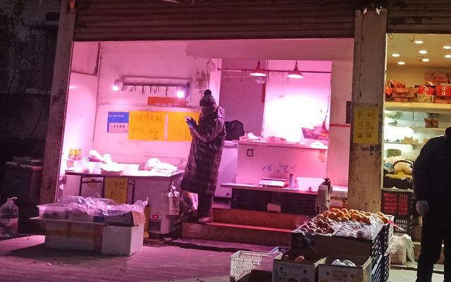 11月30日晚，朝阳区劲松街道武圣路，卖肉的小摊贩被红色灯光笼罩。新京报记者 吴梦真 摄
