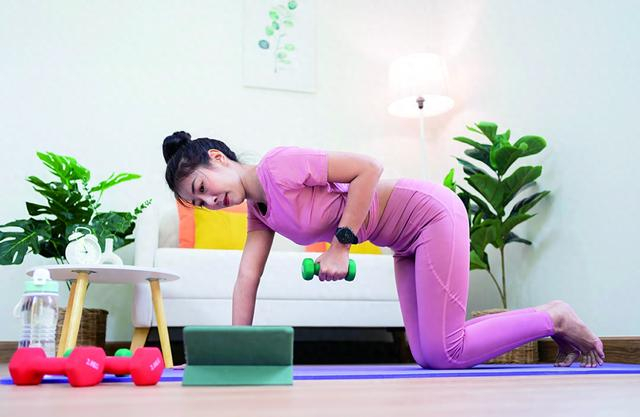 图片说明： 一名女性在家跟着电脑健身。（视觉中国）