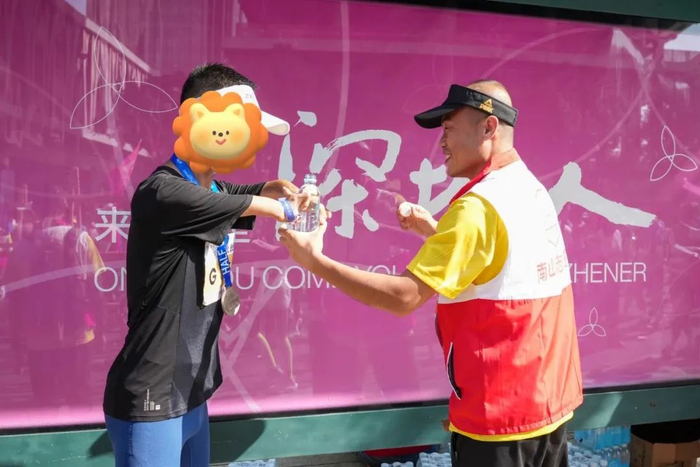 志愿者为参加马拉松的残疾跑者打开矿泉水。