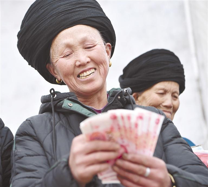     松桃自治县盘石镇采取“合作社+农户”组织方式，发展油茶产业。图为过洲村为村民发放分红金。 龙元彬 摄 （贵州图片库发）