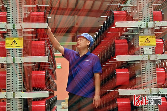 12月1日，河北鹤煌网业股份有限公司车间内，工人在检查网丝整经工序中是否有断丝、绕丝情况。河北日报记者焦磊摄