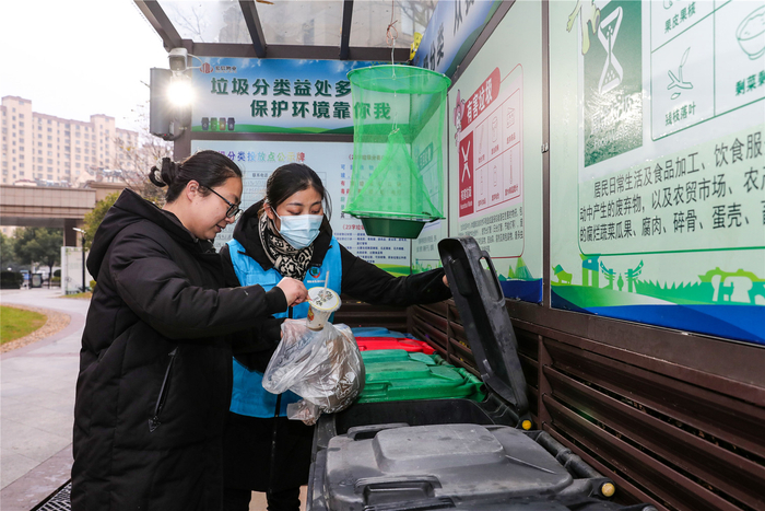 近日，在铜陵市铜官区官塘社区毓秀天城小区的垃圾分类亭，志愿者正在指导小区居民正确投放垃圾。本报通讯员 高凌君 摄