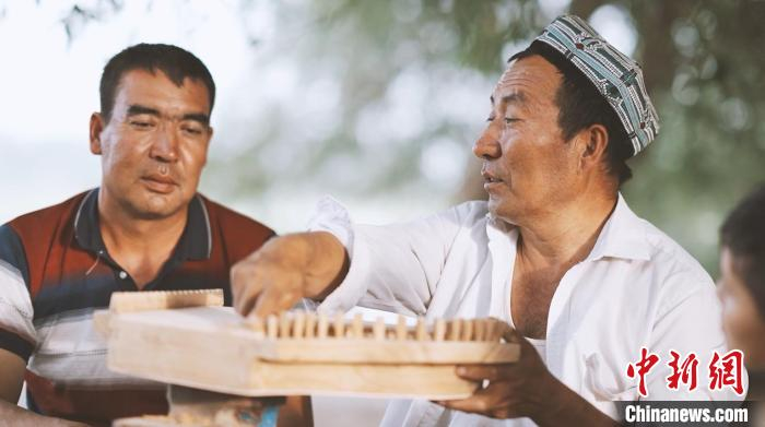 艾麦尔·依米尔在家中给徒弟讲解卡龙琴的制作过程。左丹丹 摄