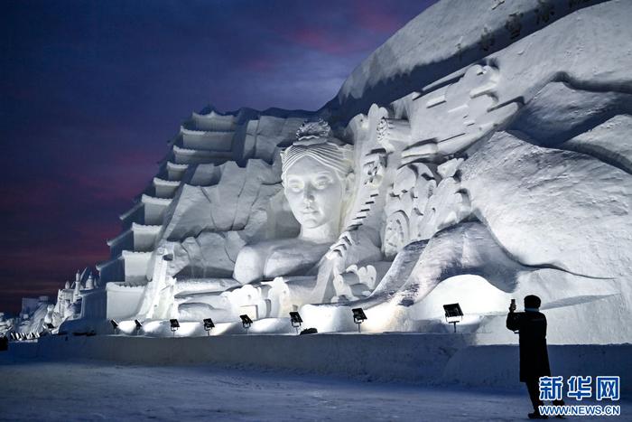 696912月12日,游客在长春冰雪新天地的一处雪雕拍照